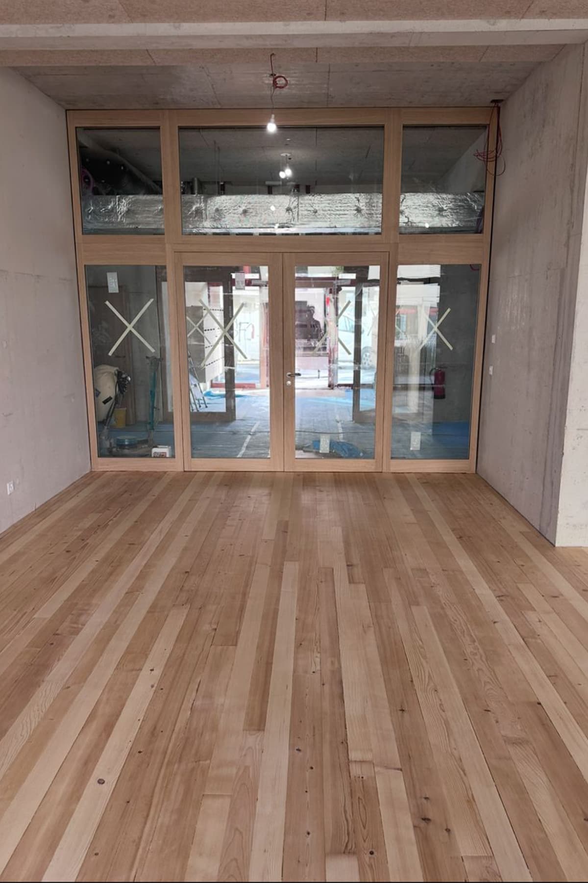 Entrée d'un local commercial avec encadrement bois, double porte vitrée et parquet massif