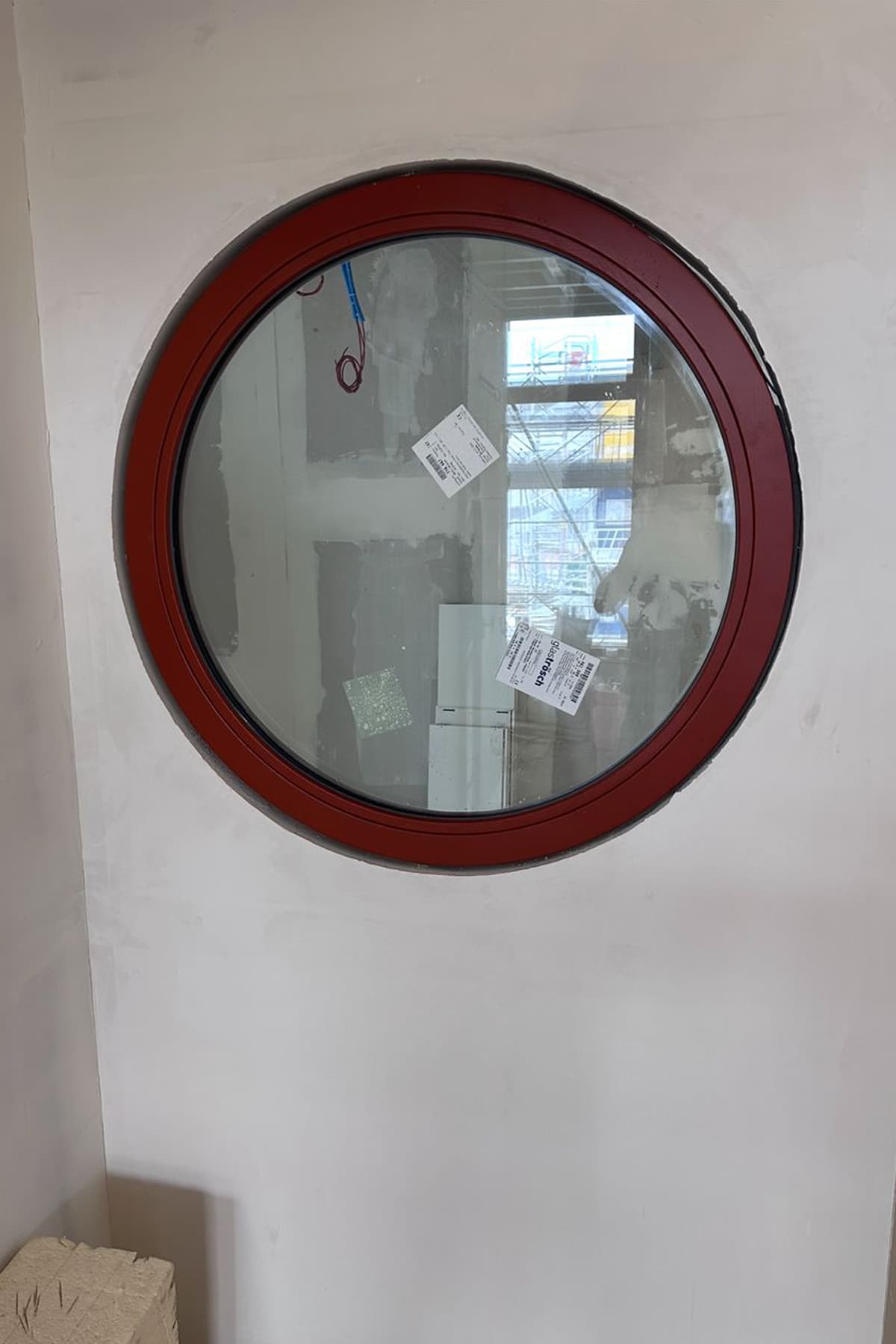 Oculus rond vitré sur mesure avec encadrement rouge intégré dans une cloison intérieure