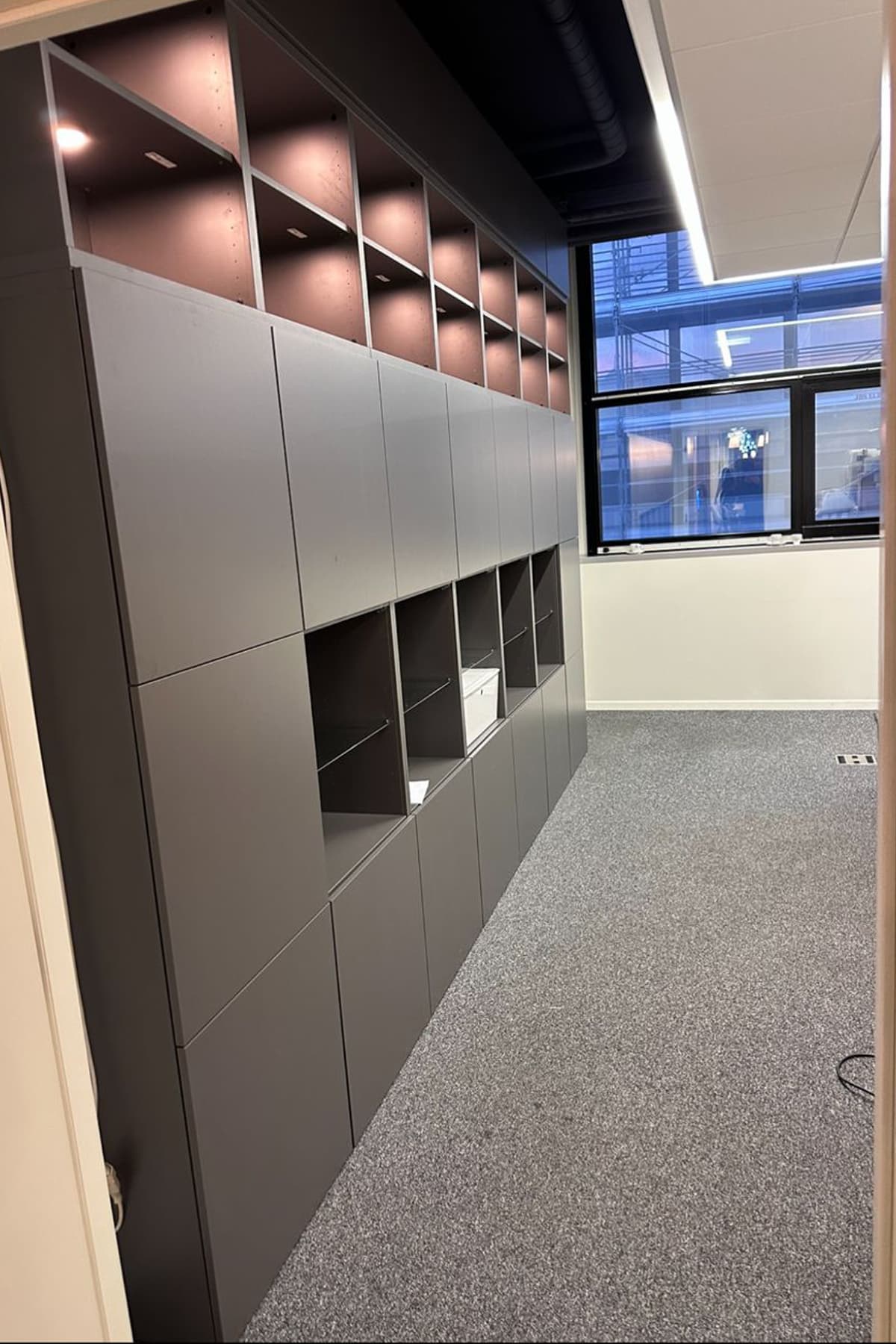 Rangements muraux sur mesure anthracite avec niches éclairées LED dans un couloir de bureaux